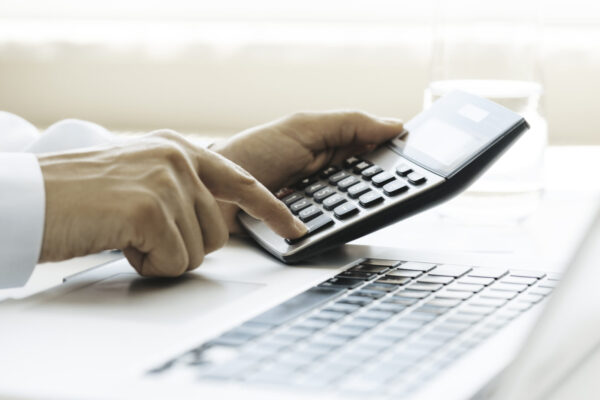 Hands of an unrecognizable person is using laptop and calculator.